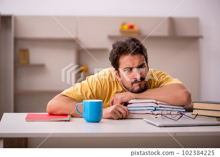 Young male student preparing for exams at home 102384225