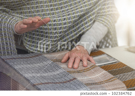 An elderly woman sells knitted items of her own production. Small business concept. An elderly woman sells knitted items of her own production. Small business concept. 102384762