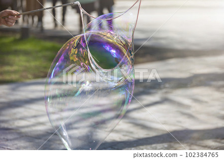 A man makes a huge soap bubble in the park. Summer fun in the park for the whole family. 102384765