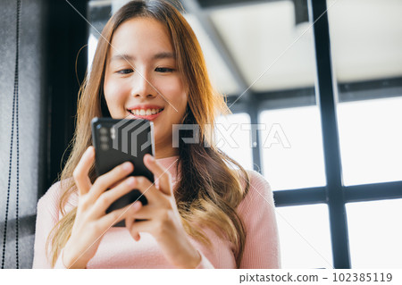 Asian young woman hands holding mobile phone at cafe coffee shop, Happy beautiful female typing text message on smart phone device and enjoyment lifestyle with social networking media 102385119