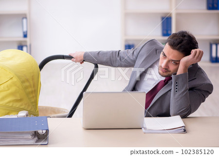 Young male employee looking after newborn at workplace 102385120