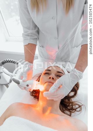 A professional cosmetologist performs a hardware anti-aging procedure in a beauty salon. Demonstrates effectiveness of technology that reduces wrinkles, improves the color scheme skin and its texture. A professional cosmetologist performs a hardware anti-aging procedure in a beauty salon. Demonstrates effectiveness of technology that reduces wrinkles, improves the color scheme skin and its texture. 102385474