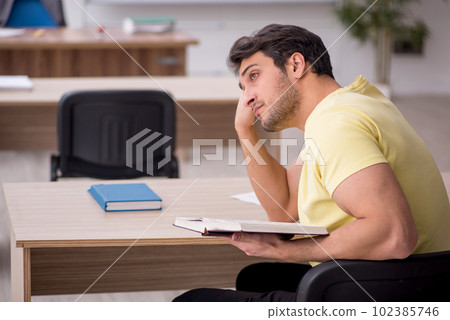 Young male student teacher sitting in the classroom 102385746