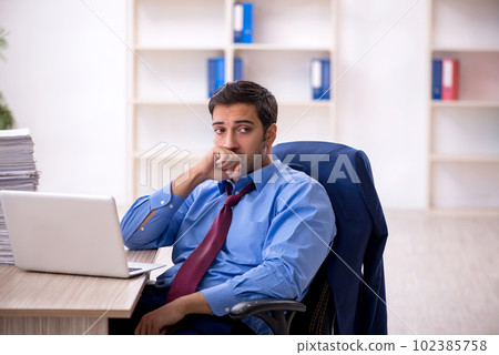 Young male employee and too much work in the office 102385758