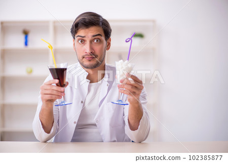 Young male chemist examining soft drink at the lab 102385877