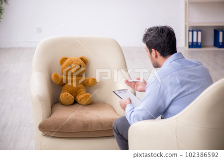 Young male psychologist meeting with toy bear Young male psychologist meeting with toy bear 102386592