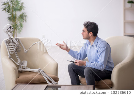 Young male psychologist meeting with skeleton Young male psychologist meeting with skeleton 102386610