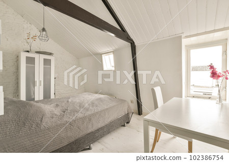 a bedroom with a bed, table and chair next to a window that has white paint on the wall behind it 102386754