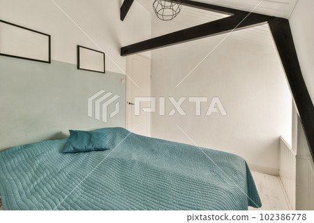 a bed in a room with white walls and wood beams on the ceiling above it is a blue comforter 102386778