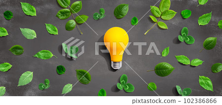 Yellow light bulb with green leaves 102386866