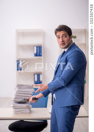 Young male employee unhappy with excessive work in the office 102387438