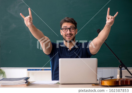 Young male music teacher sitting in the classroom Young male music teacher sitting in the classroom 102387853
