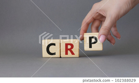 CRP - C-Reactive Protein Test symbol. Wooden cubes with word CRP. Doctor hand. Beautiful grey background. Medical and C-Reactive Protein Test concept. Copy space. 102388029