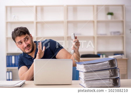 Young male employee sitting at workplace Young male employee sitting at workplace 102388210