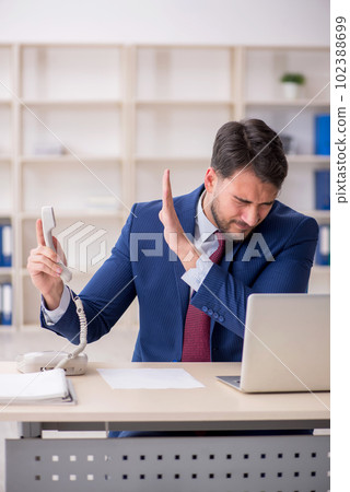 Young male employee speaking by phone at workplace 102388699