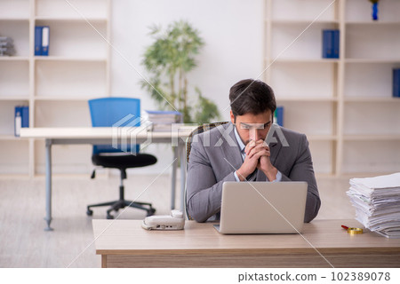 Young male employee and too much work in the office Young male employee and too much work in the office 102389078