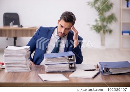 Young male employee and too much work in the office 102389497