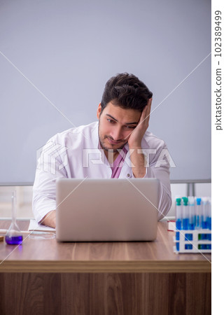 Young male chemistry teacher sitting in the classroom 102389499