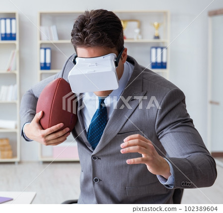Businessman playing virtual reality football in office with VR g 102389604