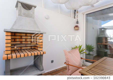Modern eco-friendly barbecue on the terrace of the apartment with a table. 102390643