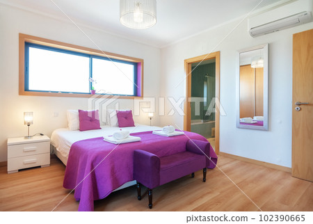 Modern bedroom with a large double bed in pink tones with towels. bathroom for customers. 102390665