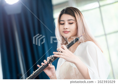 Portrait of Young Female Musician Playing Clarinet. Rehearsal before performing on stage. Portrait of Young Female Musician Playing Clarinet. Rehearsal before performing on stage. 102391029