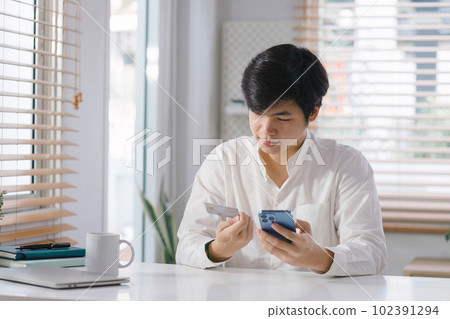 Cropped shot of millennial man is paying with a credit card online while placing orders via mobile internet and making transactions using a mobile banking application. 102391294