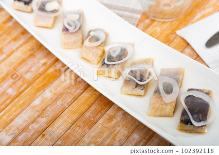 Salted pickled herring fish served on a ceramic plate Salted pickled herring fish served on a ceramic plate 102392118