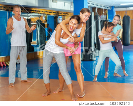 Asian woman trying to escape rear bear hug technique in self defense course 102392143
