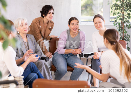 Friendly group of women discussing sitting on chairs in circle Friendly group of women discussing sitting on chairs in circle 102392202