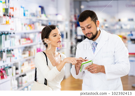 Male pharmacist advising woman customer in drugstore Male pharmacist advising woman customer in drugstore 102392413
