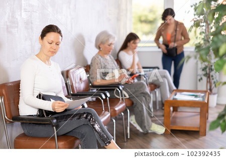 Woman is sitting in the lobby of a large company, waiting for her turn to see specialist in office Woman is sitting in the lobby of a large company, waiting for her turn to see specialist in office 102392435