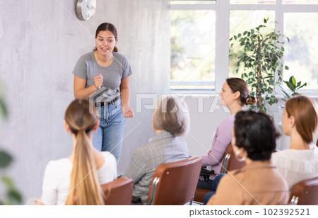 woman lecturer speaks to small audience of listeners and talks about trends, news , innovations 102392521