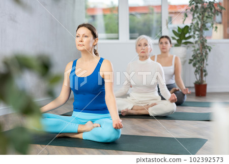 Young woman sitting in Padmasana yoga position with hands in mudra Young woman sitting in Padmasana yoga position with hands in mudra 102392573