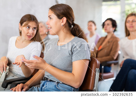 girls are sitting in lecture hall and enthusiastically whispering about latest news of university. 102392635