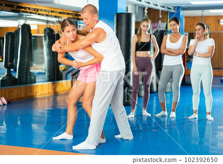 Young woman trying to escape rear bear hug technique in self defense course 102392650