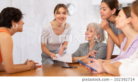 Young woman friendly talking to female colleagues in office 102392714