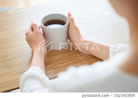 A woman's hand holding a mug and thinking 102392989
