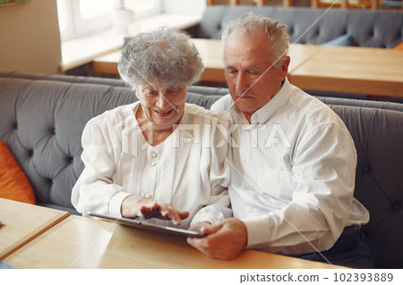 Grandparents in a cafe. Old people use the laptop. Senior in a white shirt. 102393889
