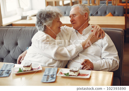 Old couple in a cafe. Grandparents eatting a dessert. Woman in a white shirt. 102393890