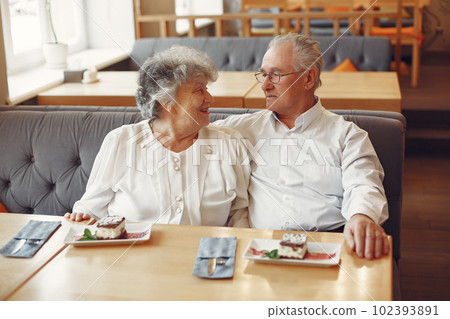 Old couple in a cafe. Grandparents eatting a dessert. Woman in a white shirt. 102393891