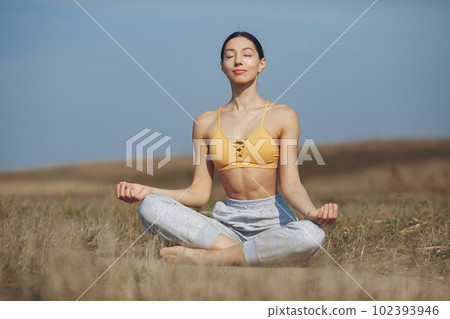Beautiful girl training on a sky background. Woman in a yellow top. Lady make a yoga 102393946