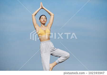 Beautiful girl training on a sky background. Woman in a yellow top. Lady make a yoga Beautiful girl training on a sky background. Woman in a yellow top. Lady make a yoga 102393947