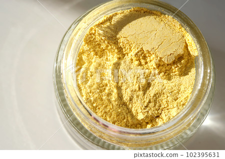 An open jar of a yellow turmeric facial scrub showing off its texture. An open jar of a yellow turmeric facial scrub showing off its texture. 102395631