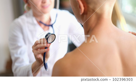 Female doctor listening heart or lungs of man patient with stethoscope 102396303