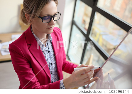 Business woman writing information on board in office Business woman writing information on board in office 102396344