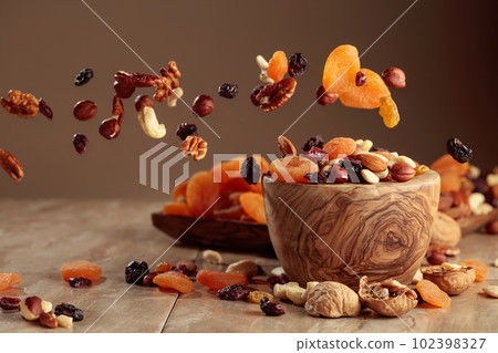 The mix of nuts and raisins in a wooden bowl. The mix of nuts and raisins in a wooden bowl. 102398327