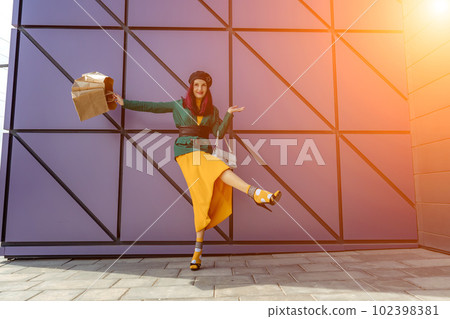 A happy shopaholic girl throws her bags near a shopping center. 102398381