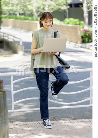 A female college student using a laptop in the fresh green A female college student using a laptop in the fresh green 102398688