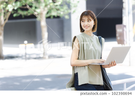 A female college student using a laptop in the fresh green A female college student using a laptop in the fresh green 102398694